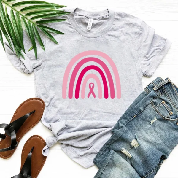 A Rainbow Shirt Pink Ribbon t-shirt and sandals on a white surface.