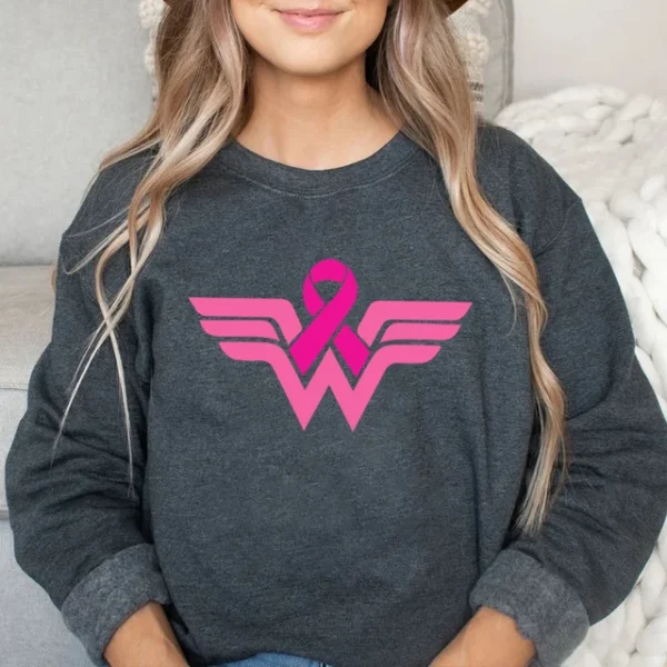 A woman wearing a Superhero Sweatshirt with a pink breast cancer ribbon.