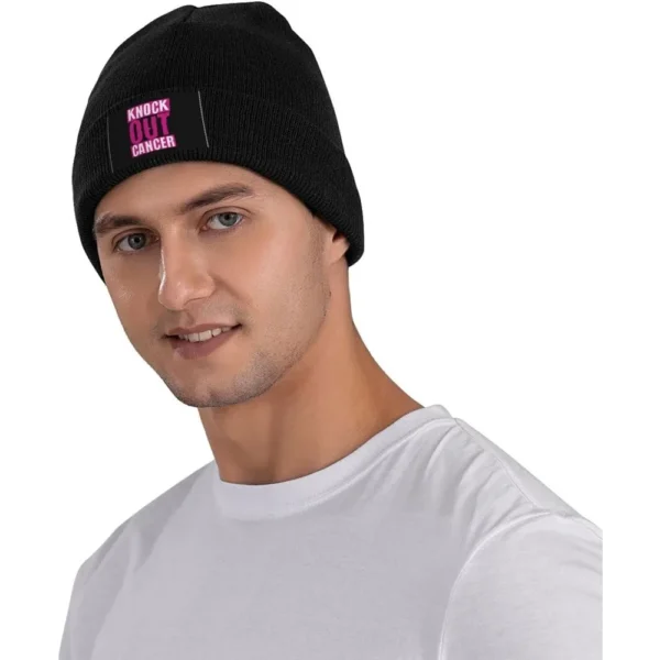 A man wearing a black Beanie Knit Cap with a pink logo.