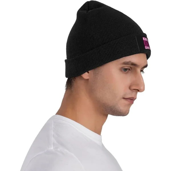 A man wearing a black Beanie Knit Cap with a pink tag on it.