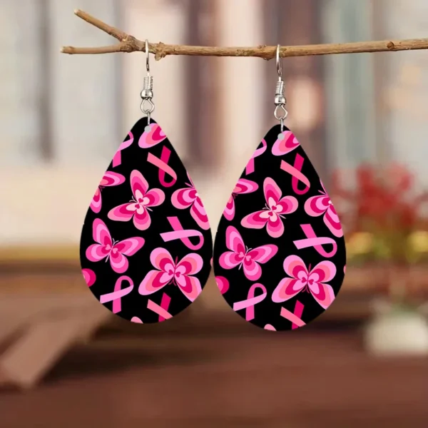 A pair of pink and black water drop earrings hanging from a branch.