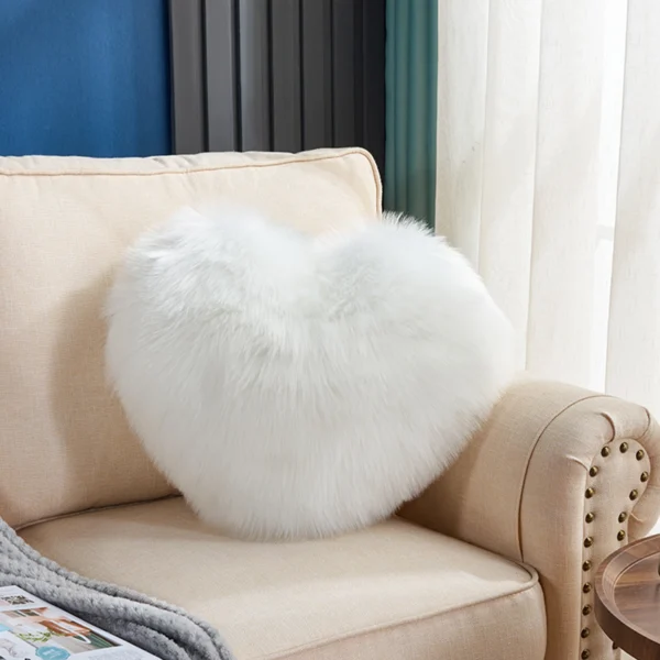 A soft plush heart shaped pillow on a couch.